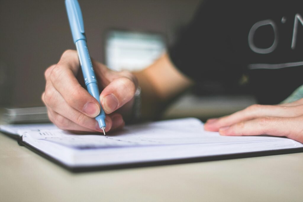 Close up of hand writing in notebook using a blue pen