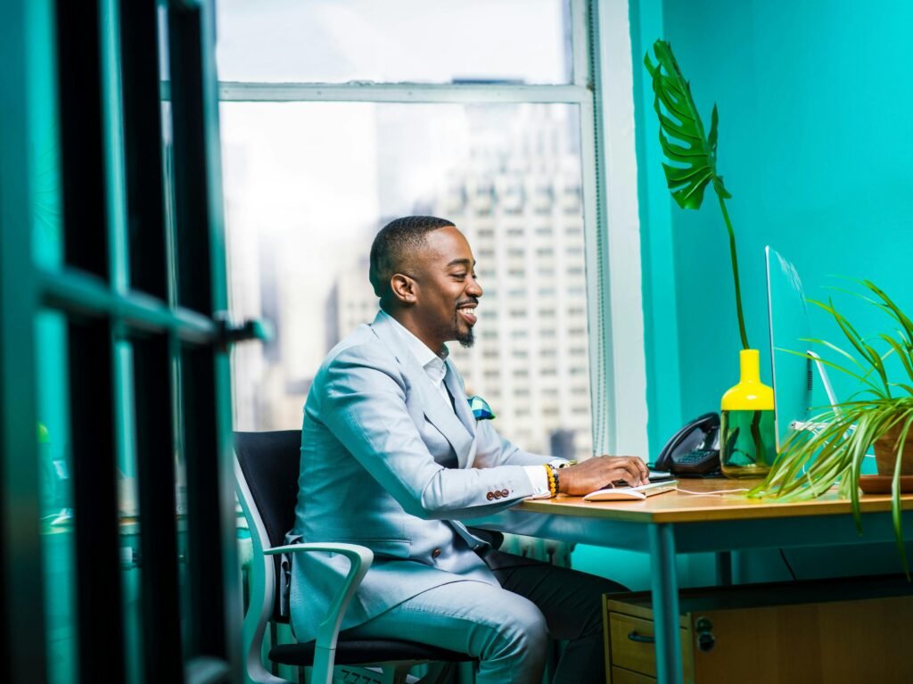 Confident businessman in modern office working on laptop with city view