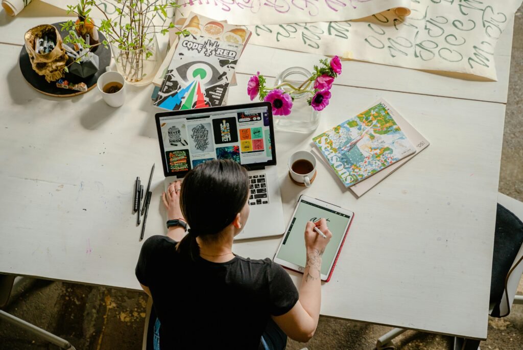 Artistic workspace featuring calligraphy and digital design on a tablet and laptop